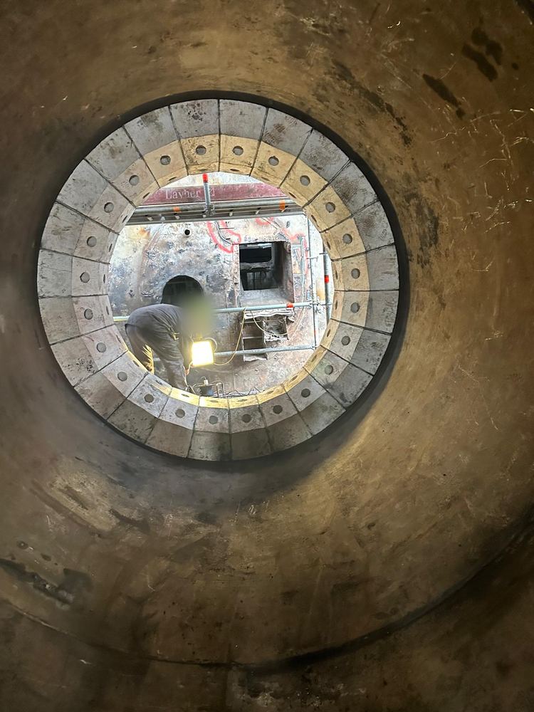 Compagnon au travail vu à travers une ouverture circulaire de chaudière