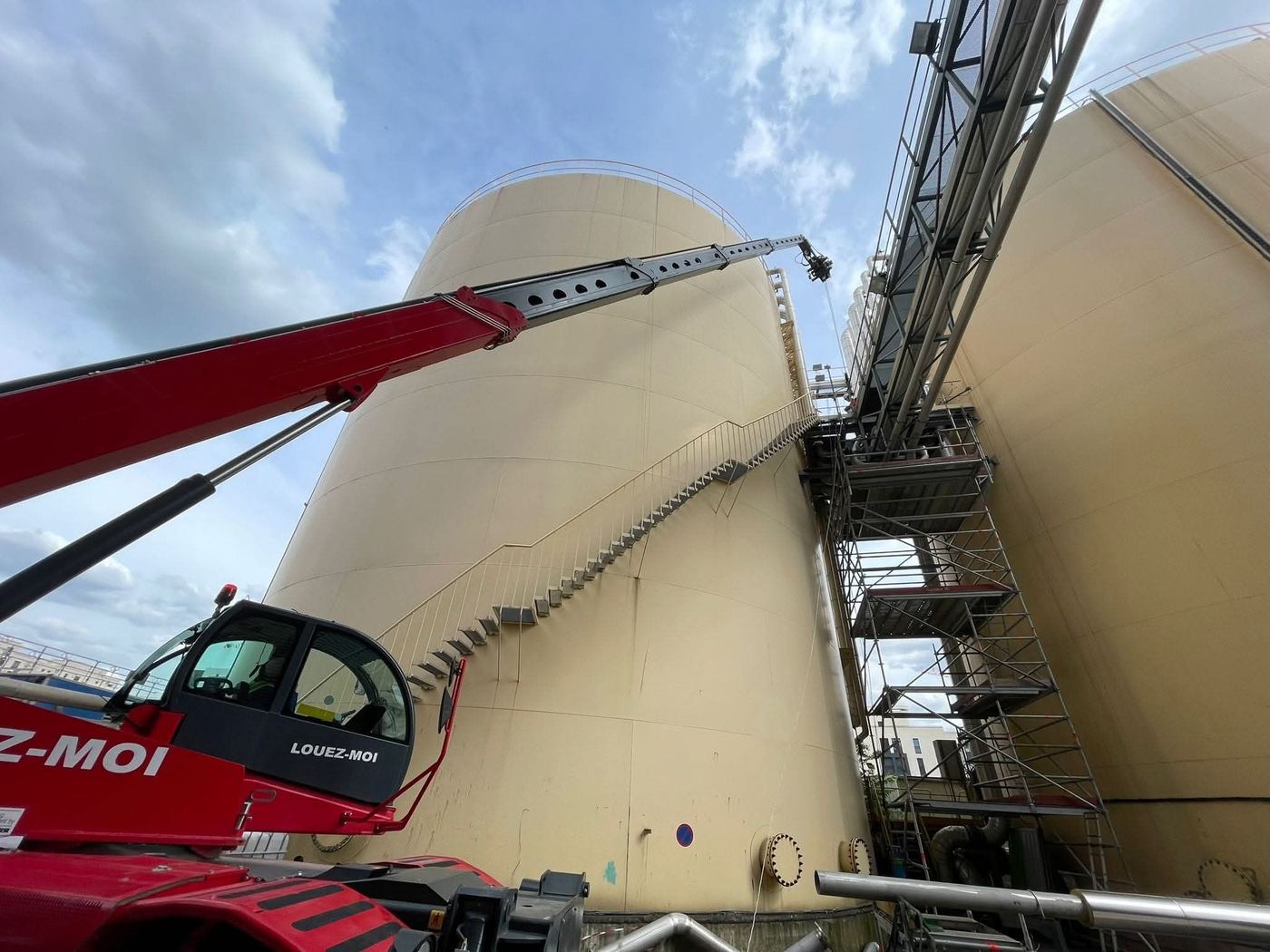 Réservoir industriel et échafaudage pendant un chantier de tuyauterie